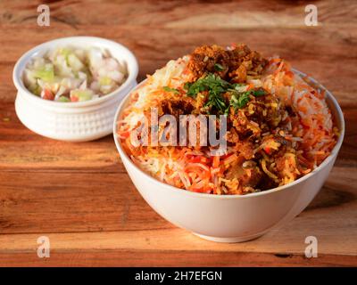 Kashmiri Mutton Gocht ou Lamb Biryani préparé en riz Basmati servi avec de l'oignon sur fond de bois rustique, foyer sélectif Banque D'Images