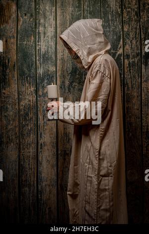 Grand homme avec robe de prêtre longue avec vieux mur en bois Banque D'Images