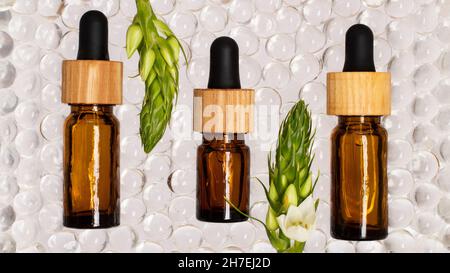 Flacons cosmétiques en verre brun avec couvercle en bois.boules d'hydrogel transparentes autour d'eux. Banque D'Images