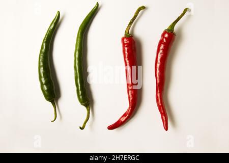 Plat d'un groupe de piments rouges et verts frais vus d'en haut, isolé sur fond blanc Banque D'Images