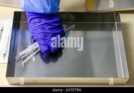 22 novembre 2021, Saxe-Anhalt, Lützen: Un employé de Malteser prend des seringues prêtes à l'emploi avec le vaccin de Biontech au centre de vaccination rouvert à Zorbau.Le district a dû fermer le centre le 1er octobre, maintenant les résidents peuvent obtenir une première, deuxième ou une vaccination de rappel du lundi au samedi de 11 h à 6 h.Les vaccins sont administrés par des vaccins de Biontech et Moderna.Outre le centre de vaccination, le district gère trois autres centres de vaccination et un bus de vaccination.Photo: Jan Woitas/dpa-Zentralbild/ZB Banque D'Images