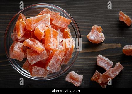 Ferme naturelle fruits de citrouille confits faits maison parsemés de sucre en poudre dans un bol en verre sur une table en bois, vue du dessus. Banque D'Images