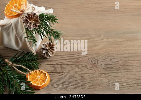 Concept de noël zéro déchet. Emballé dans un cadeau en tissu naturel et des décorations de matériaux naturels sur une table en bois, vue sur le dessus, espace de copie. Banque D'Images