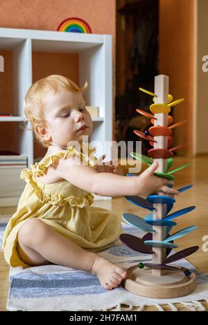 Fille riante jouant des pétales arc-en-ciel tomber des feuilles avec des perles métalliques Maria Montessori matériaux Banque D'Images