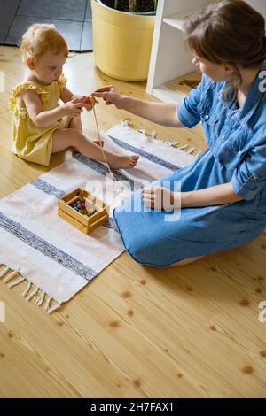 Bonne famille mère, fille et chat passer du temps ensemble à jouer des matériaux Maria Montessori Banque D'Images