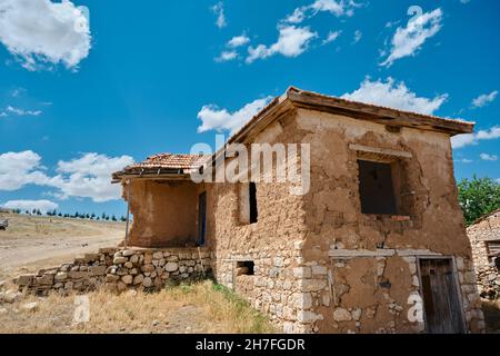 Une petite maison de village en pierre et en boue avec un ciel magnifique et un fond de nuages blancs établie dans le champ agricole en anatolie en Turquie Banque D'Images