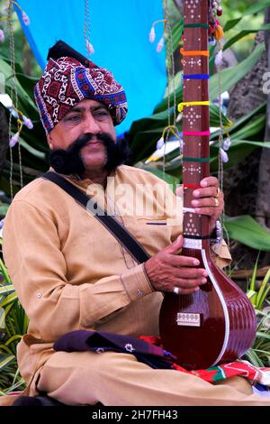 Pune, Maharashtra / Inde - 18 novembre 2021 : chanteur folklorique Rajasthani avec turban et moustache avec un instrument de musique à l'événement du Festival local. Banque D'Images