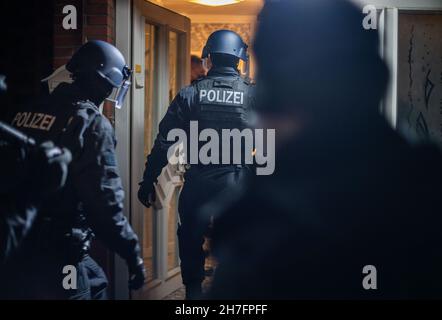 23 novembre 2021, Rhénanie-du-Nord-Westphalie, Gütersloh : les forces de police s'empagent dans une maison pour la rechercher.La police a arrêté plusieurs suspects lors de raids simultanés dans plusieurs pays contre des soi-disant «calmars de bâches».On dit qu'il s'agit de gangs de voleurs qui volent des charges de camions.Photo: Lino Mirgeler/dpa Banque D'Images