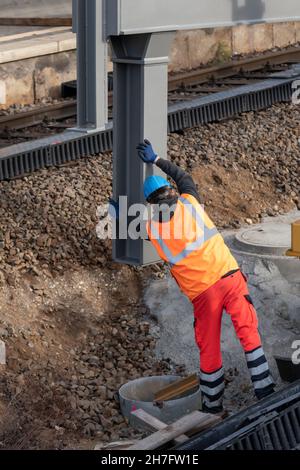 Un travailleur aligne un gros composant en acier avant de l'abaisser Banque D'Images