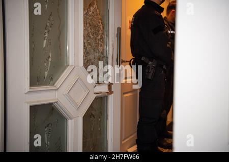23 novembre 2021, Rhénanie-du-Nord-Westphalie, Gütersloh : les policiers se tiennent à côté de la porte détruite d'une maison qu'ils ont fouillée.La police a arrêté plusieurs suspects lors de raids simultanés dans plusieurs pays contre des soi-disant «calmars de bâches».On dit qu'il s'agit de gangs de voleurs qui volent des charges de camions.Photo: Lino Mirgeler/dpa Banque D'Images