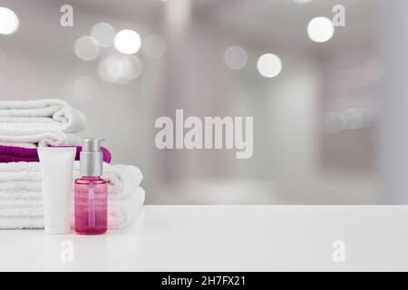 Spa encore la vie avec des serviettes et des cosmétiques de soin de la peau sur fond flou Banque D'Images