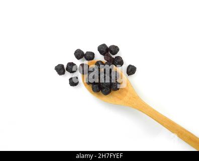 Baies d'aronia séchées dans une cuillère en bois isolée sur fond blanc Banque D'Images