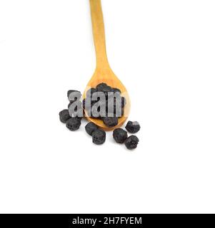 Baies d'aronia séchées dans une cuillère en bois isolée sur fond blanc Banque D'Images