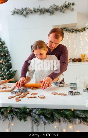 Père avec sa fille cuisiner faire du pain d'épice, couper des biscuits de pâte de pain d'épice, s'amuser.Repas de fête, processus de cuisson, cuisine familiale, Chr Banque D'Images