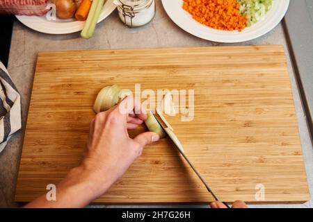 Une femme avec un couteau coupe l'oignon sur des tranches pour la cuisson Banque D'Images