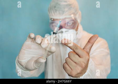 un médecin en costume protecteur tient une seringue contenant le vaccin contre le coronavirus covid 19 Banque D'Images