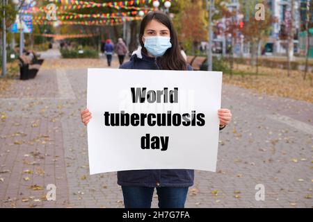 Une femme dans un masque médical tient une affiche avec le texte Journée mondiale de la tuberculose Banque D'Images