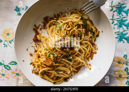 plat de pâtes italien maison, connu sous le nom de « pâtes le sarde » sur un linge de table, composé de spaghetti, sardines, persil, pignons et chapelure.Classique i Banque D'Images