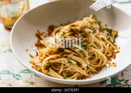 plat de pâtes italien maison, connu sous le nom de « pâtes le sarde » sur un linge de table, composé de spaghetti, sardines, persil, pignons et chapelure.Classique i Banque D'Images