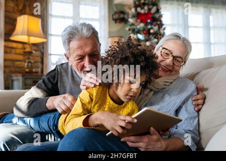 Portrait de grands-parents heureux avec une petite fille utilisant une tablette numérique à la maison Banque D'Images