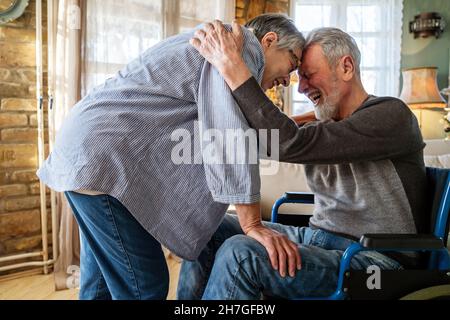 Homme mature ayant un handicap en fauteuil roulant passant du temps avec sa femme à la maison Banque D'Images