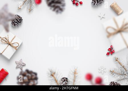 Les décorations de Noël tombent sur le concept de table blanche.Cadeaux, pin, cônes, baies rouges, branches d'arbre,flocons de neige.Vue du dessus, plat, carte de vœux c Banque D'Images