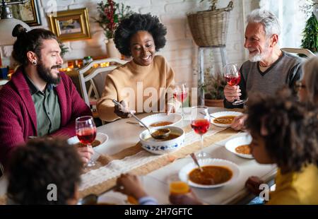 Bonne famille multiethnique multigénération s'amusant autour d'une table de cuisine. Banque D'Images