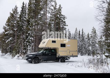Minibus sur route enneigée dans la forêt en hiver, près d'Arvidsjaur, Laponie, Suède Banque D'Images