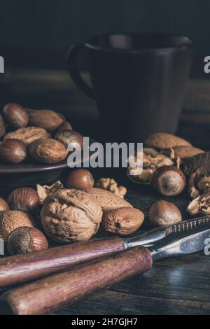Gros plan d'une sélection de noix mélangées dans leur coque avec des casse-noisettes et un espace de copie Banque D'Images