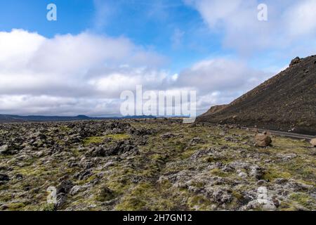 Vue à angle bas du paysage stérile de roche de lave noire, certains couverts de mousse, du volcan Katla voisin sur l'Islande avec des montagnes à l'arrière Banque D'Images