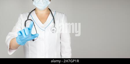 Médecin avec un stéthoscope appuie sur le bouton virtuel sur fond gris Banque D'Images