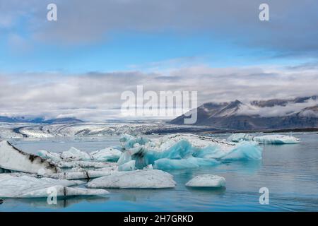 Vue panoramique sur le lagon glaciaire avec le terminus ou la fin du glacier de Jokulsarlon, Islande avec en avant-plan divers icebergs bleus de l'arctique Banque D'Images