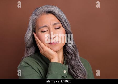 Photo de malade vieilli blanc coiffure dame main joue chemise isolée sur fond brun couleur Banque D'Images