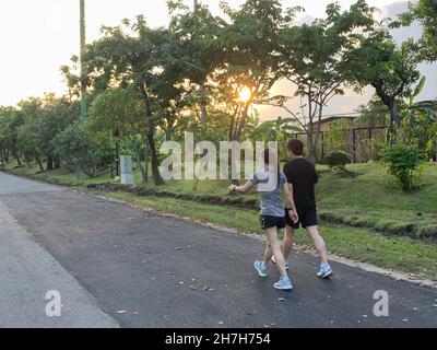 Couple faire de l'exercice en marchant ensemble dans le parc au coucher du soleil concept de mode de vie sain. Banque D'Images