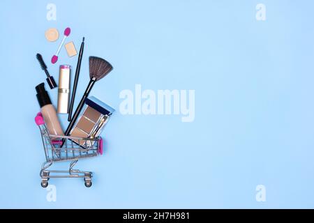 Produits de maquillage et brosses dans le panier sur fond bleu.Concept de vente de cosmétiques de maquillage.Copier l'espace Banque D'Images