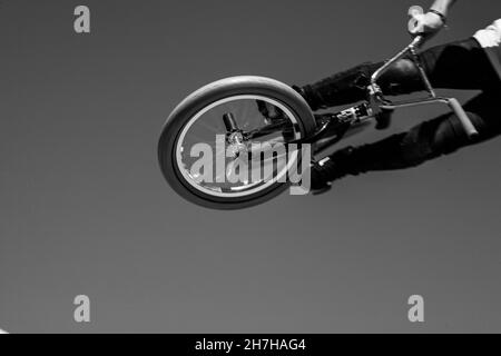 Boy doing jump trick avec son BMX au skatepark Banque D'Images