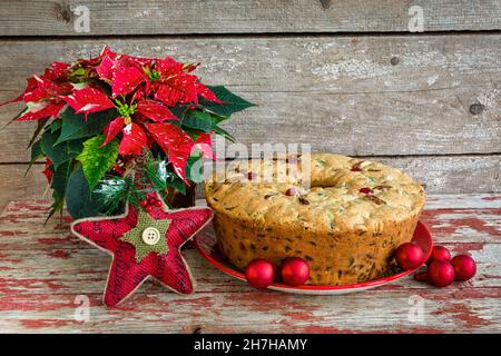 Gâteau de Noël traditionnel avec poinsettia et décorations de Noël sur fond de bois rustique. Banque D'Images