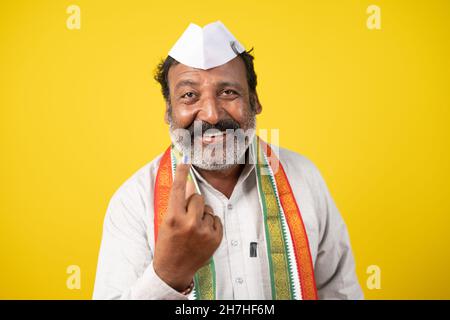 Un homme politique souriant et souriant montrant un doigt marqué d'encre après avoir voté dans les sondages d'élections - le concept de l'élection indienne et du système démocratique