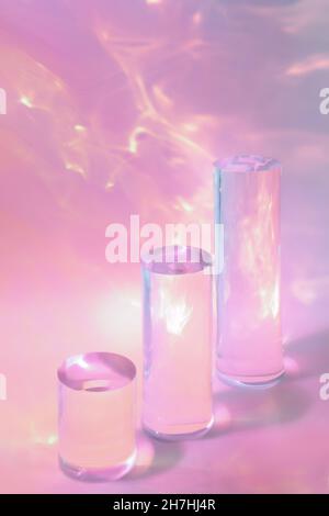 trois podiums en verre transparent sur fond rose pastel Banque D'Images