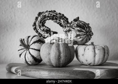 une sélection de mini décorations de citrouille colorées et variées présentées sur une planche à découper en bois Banque D'Images