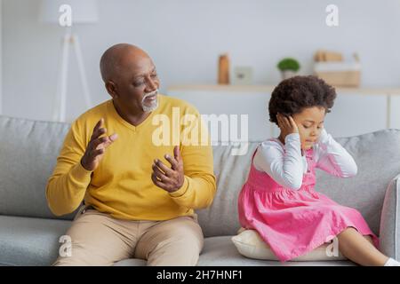 Bouleversée triste noir petite fille ferme ses oreilles et ne veut pas écouter l'homme âgé Banque D'Images