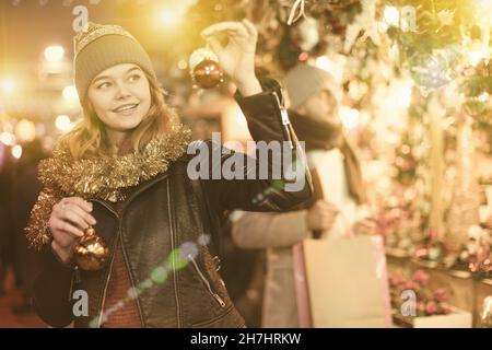 Bonne jeune femme avec des jouets de Noël à la foire Banque D'Images