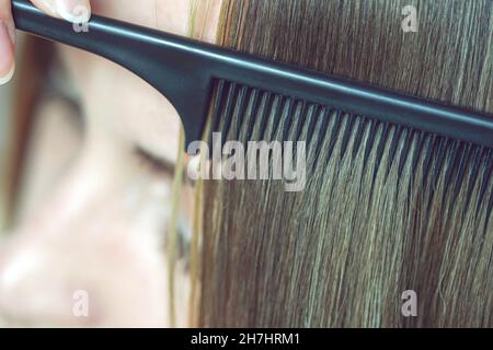 Le processus de combinaison d'un peigne fin noir pour les cheveux bruns. Banque D'Images