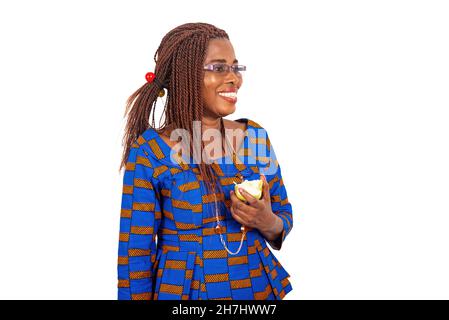 belle femme d'affaires adulte debout tenant une pomme fraîche et regardant de côté souriant. Banque D'Images