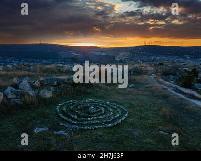 Labyrinthe en spirale fait de pierres au coucher du soleil. Banque D'Images