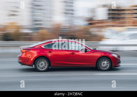 Ukraine, Kiev - 23 novembre 2021 : la voiture rouge MAZDA 6 se déplace dans la rue.Éditorial Banque D'Images