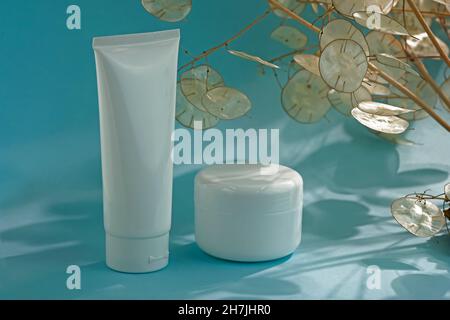Récipients en plastique blanc pour la crème sur fond bleu.Concept de cosmétiques naturels.Vider le tube blanc et le bol pour la crème. Banque D'Images