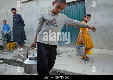 Hakim, 11 ans, recueille de l'eau potable auprès d'une pompe manuelle publique, la seule source d'eau potable dans son quartier de Kaboul, la capitale.Autre childre Banque D'Images