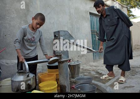 Hakim, 11 ans, recueille de l'eau potable auprès d'une pompe manuelle publique, la seule source d'eau potable dans son quartier de Kaboul, la capitale.Autre childre Banque D'Images