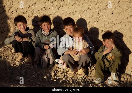 Un groupe d'enfants de la communauté ethnique Hazara s'assoient contre un mur, dans le village de Ragshad, à la périphérie de la ville de Bamyan, dans le centre de la province de Bamyan Banque D'Images